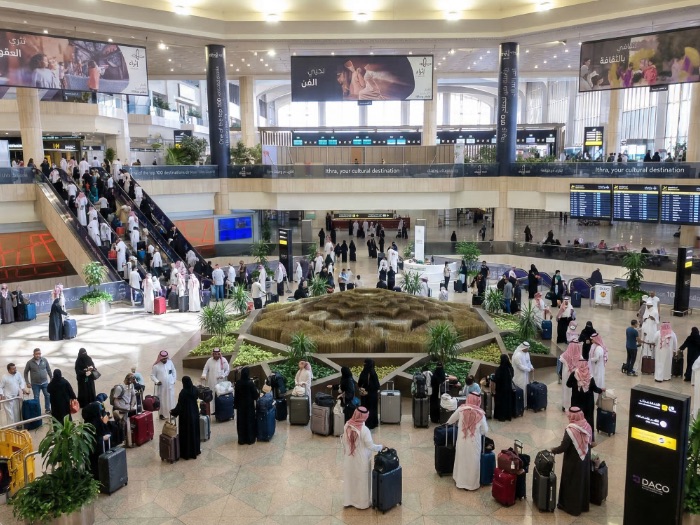 Busy international airport terminal in Saudi Arabia at King Fahd International Airport Dammam DMM with passengers arriving with their luggages and waiting to exit, representing premium airport fast track, VIP meet and assist services, and Altanfeethi.VIP elite airport concierge assistance for travelers.